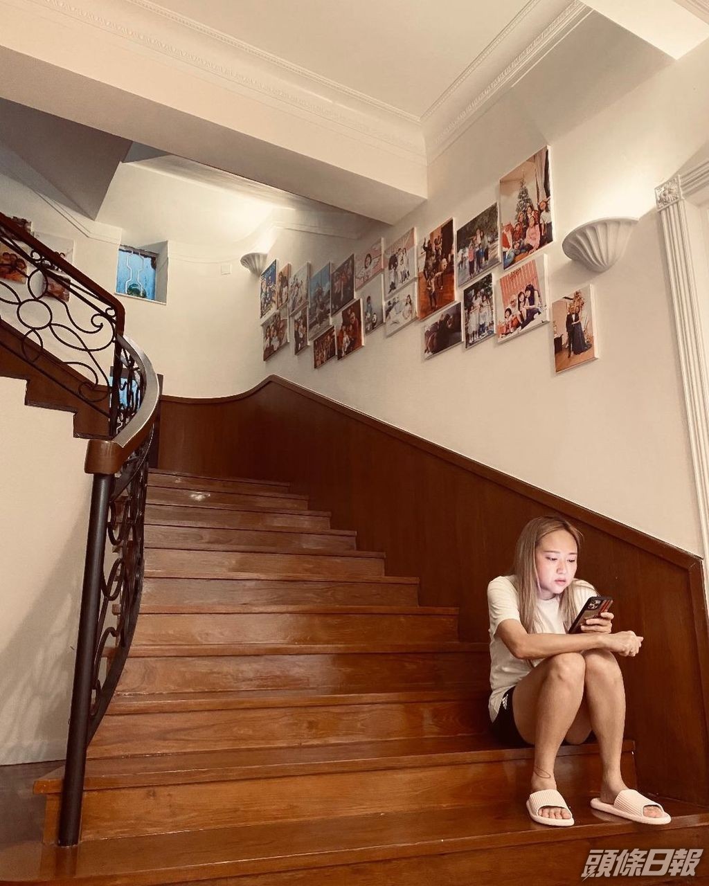 屋內往上層的樓梯，貼有多張全家照片。