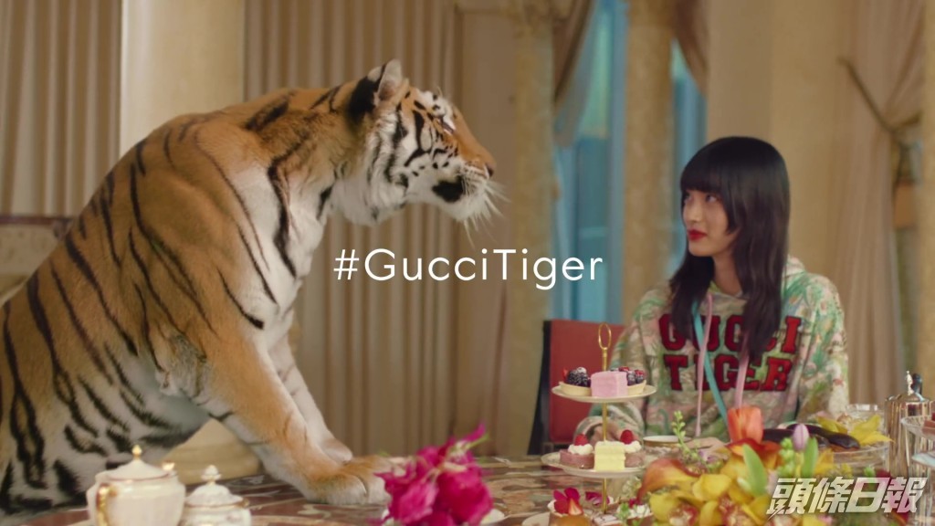 最後一幕為老虎前腿站在眾模特兒的圓形餐桌中。Gucci廣告截圖