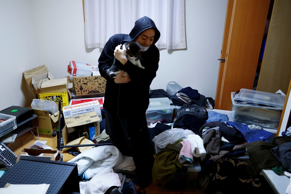 日本石川縣輪島，秋山智德抱著他的貓展示他正在打掃被地震摧毀的房子。 路透社