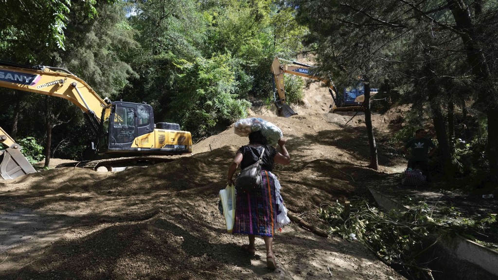 危地马拉发生地震,一名女子顶着食物走过山泥倾泻处。 美联社 危地马拉发生地震,一名女子顶着食物走过山泥倾泻处。 美联社