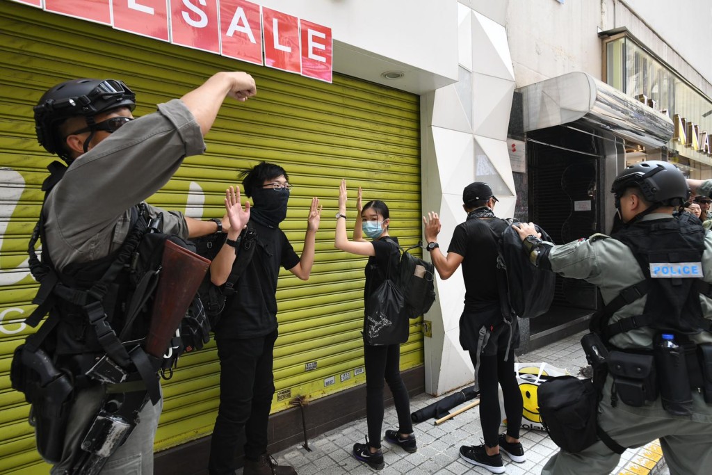 防暴警搜查在場的黑衣人士。