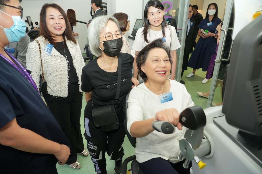 香港赛马会慈善信托基金代表锺惠敏(左二)在开幕礼后的参观团，观看嘉宾试用中心的保健运动器材。
