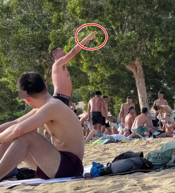 躁泳客嫌阻礙發言，改為以手拿著煙（紅圈示）。網上截圖