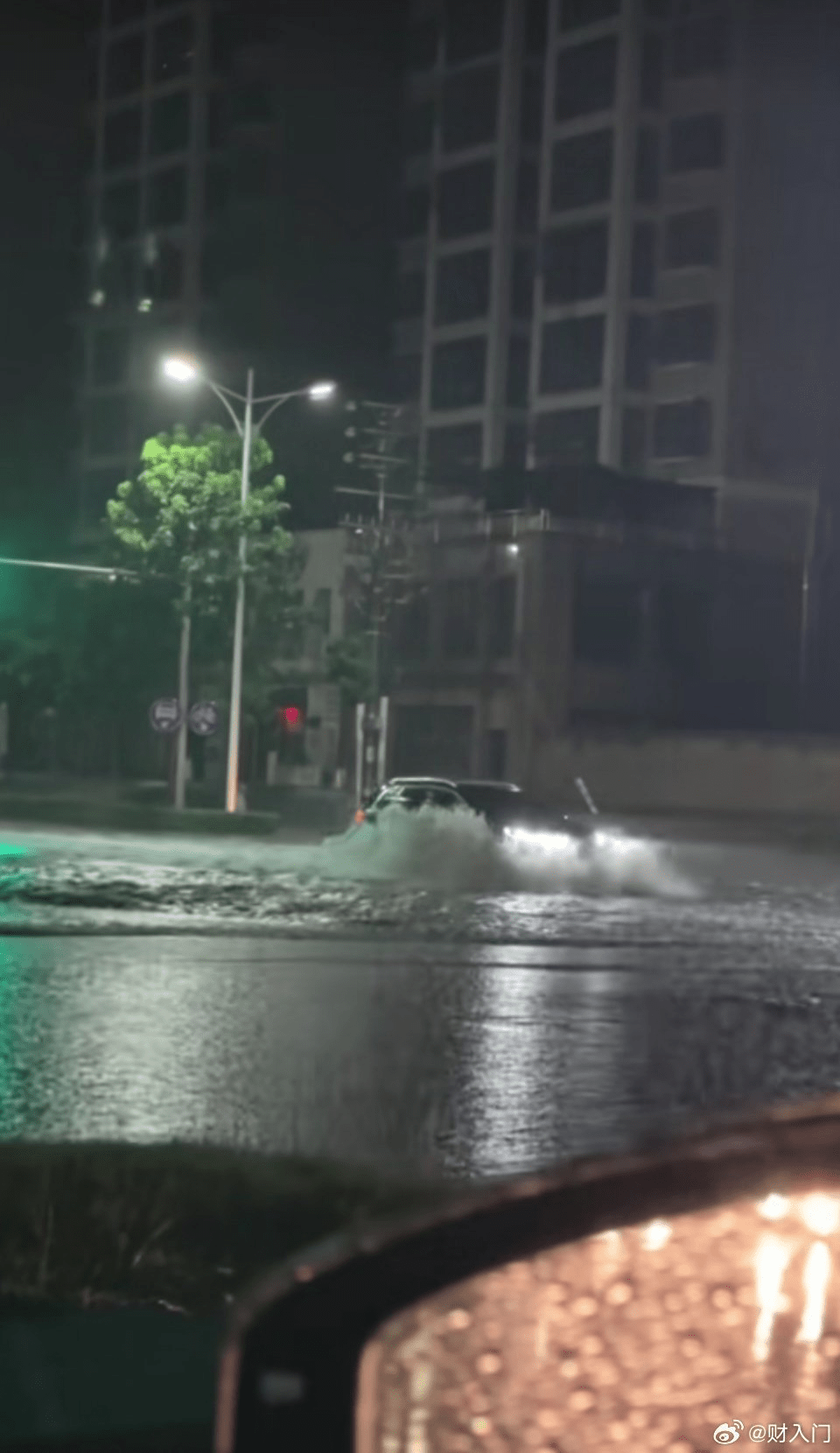 鄭州暴雨，路面積水淹沒車輪，車輛行駛掀起浪花。 