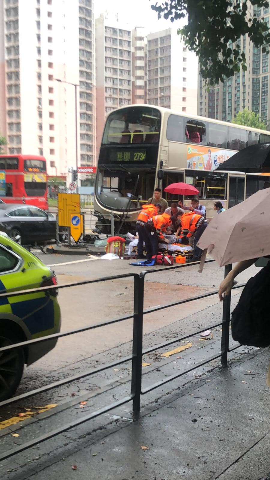 救護員為傷者施救，熱心途人打傘遮雨。網上圖片