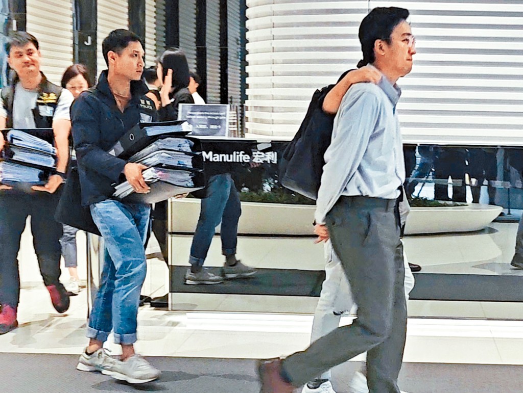 楊彧(右)被捕後由探員帶走,警方同時檢獲一批涉案文件。