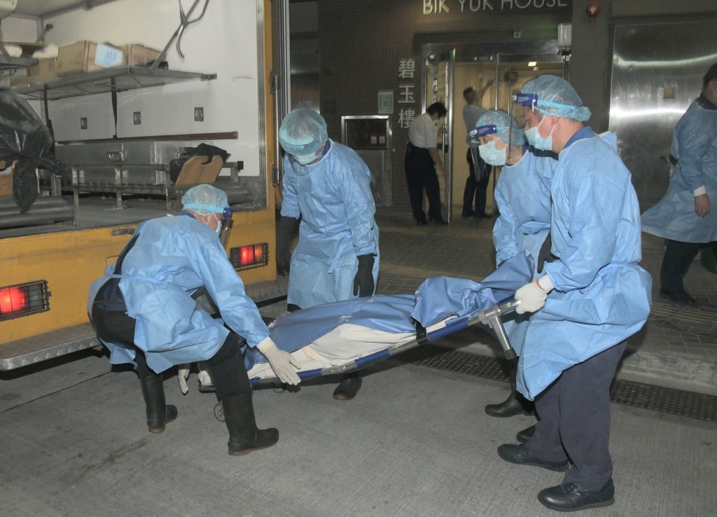 仵工將103歲女死者的遺體抬上黑箱車。