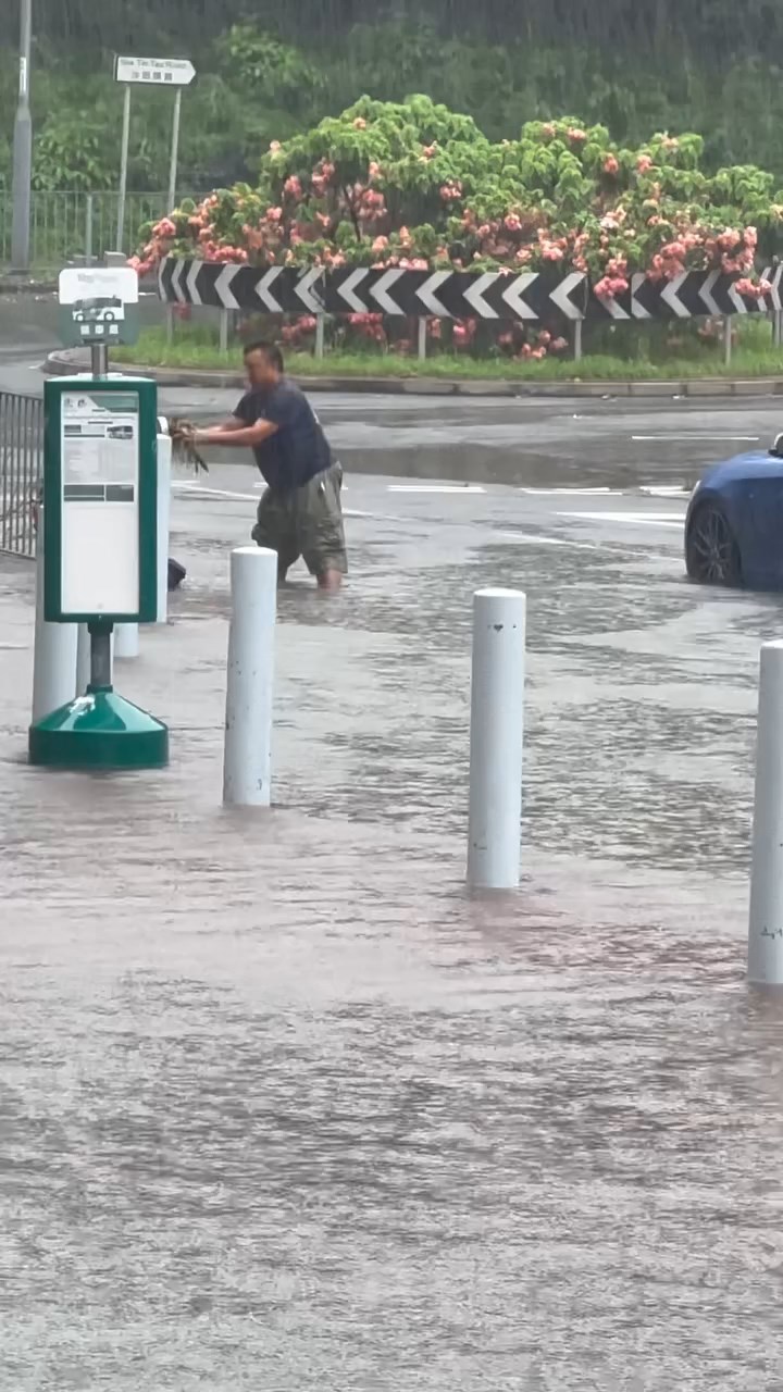 一名中年男子冒着大雨伸手落積水清走垃圾。threads@_.yuching