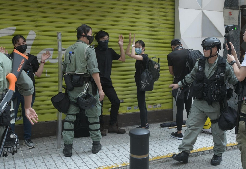 防暴警搜查在場的黑衣人士。