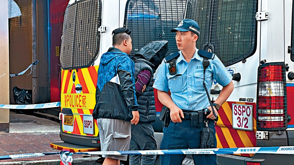 警方在深水埗拘捕兩人，其中一人黑布蒙頭，由警員扣押。