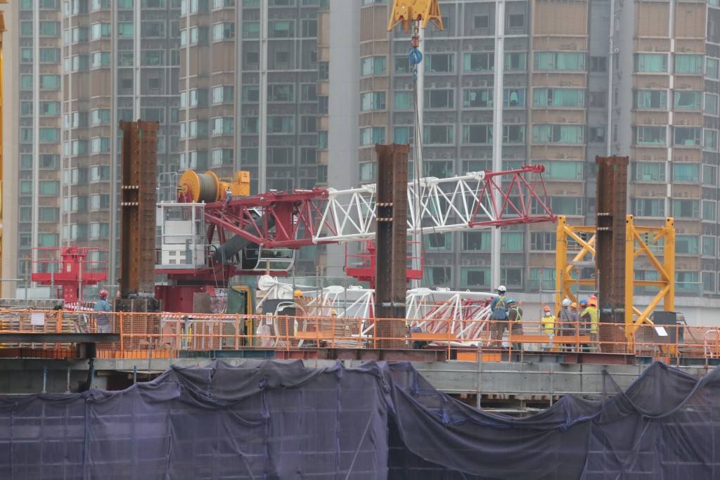西九龍高鐵站上蓋一個建築地盤天秤吊臂斷裂扭曲，工人用工具移走受損組件。(尹敬堂攝)