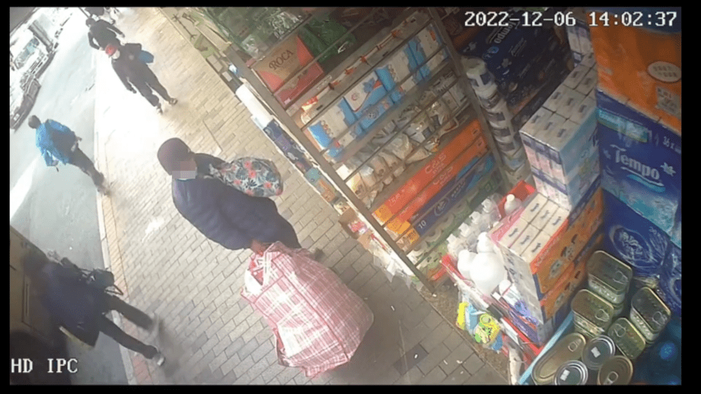 影片看到一个拖着红白蓝袋的婆婆走到药房门口。