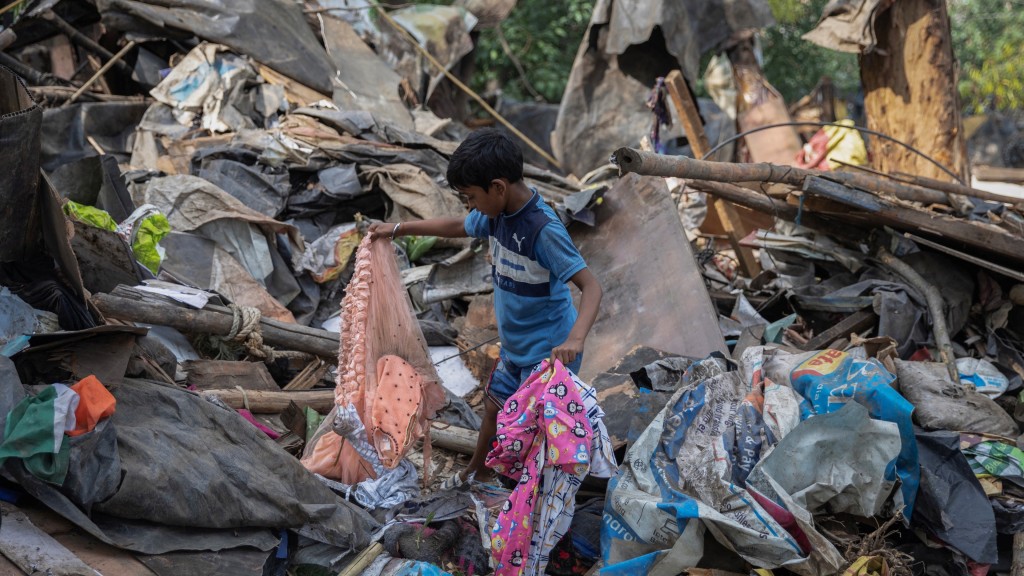 庫爾瑪（右）10歲的兒子在廢墟中拾回妹妹的一條裙子。 路透社