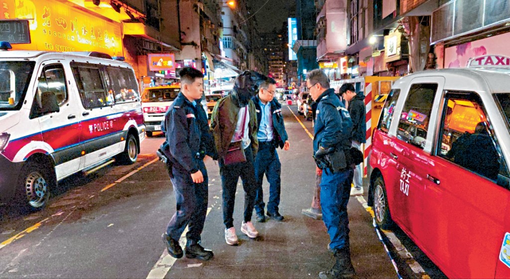 涉案的士司機被黑布蒙頭由警員押走。