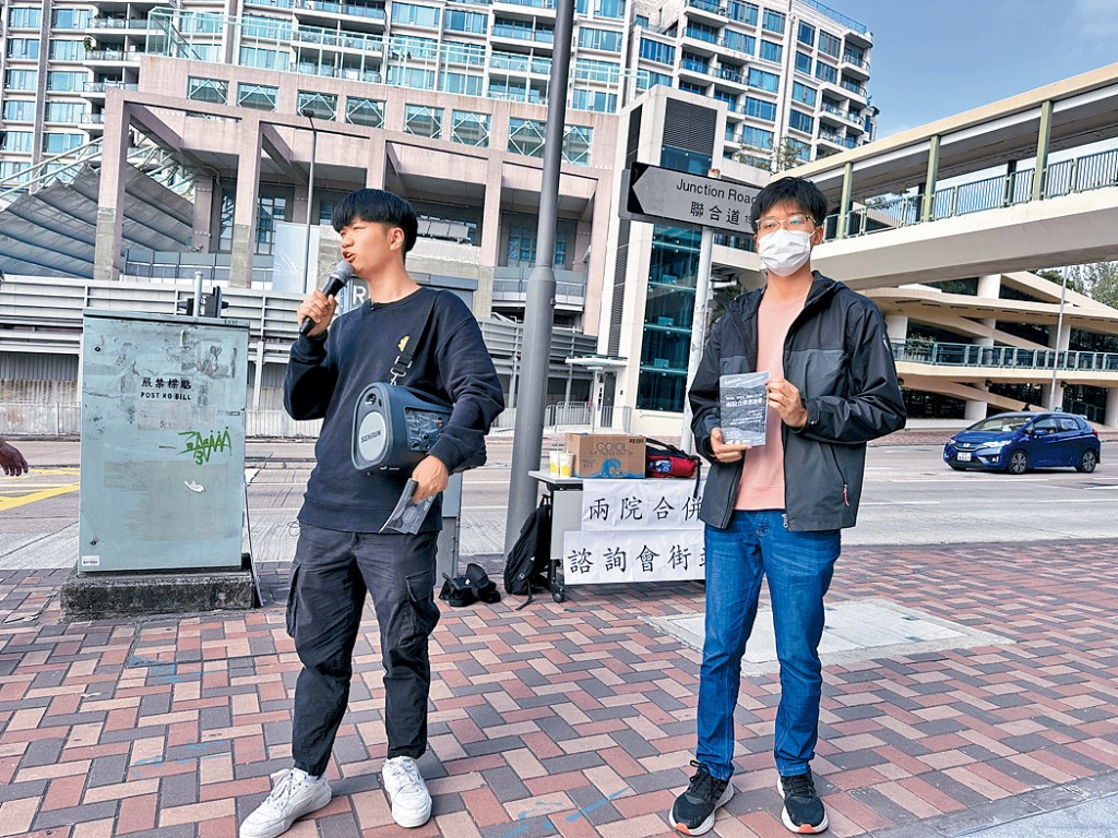 文學院社科院關注組成員戴嘉平（左）昨起於浸大校門外擺設街站及派發傳單，呼籲師生出席周四舉行的兩院合併諮詢會。