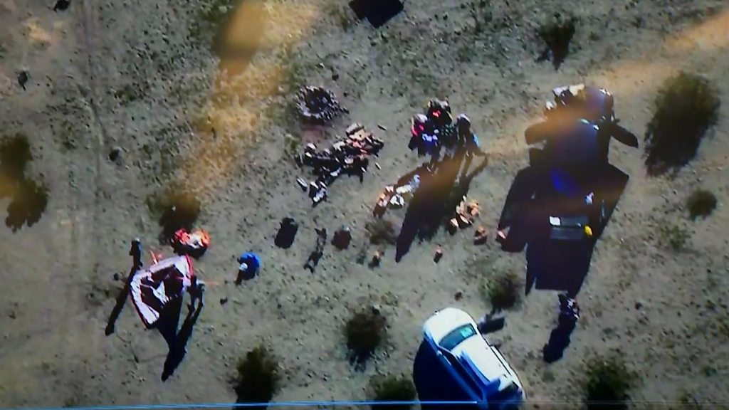 美国司法部展示嫌犯在沙漠中将一个大型黑色物体搬到桌子上的监视空拍影片。司法部图片 美国司法部展示嫌犯在沙漠中将一个大型黑色物体搬到桌子上的监视空拍影片。司法部图片