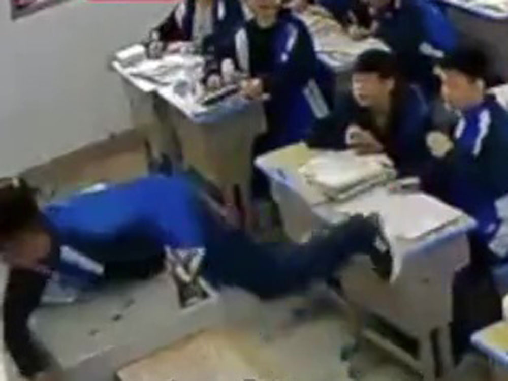挥拳后，男学生整个趴了上讲台。