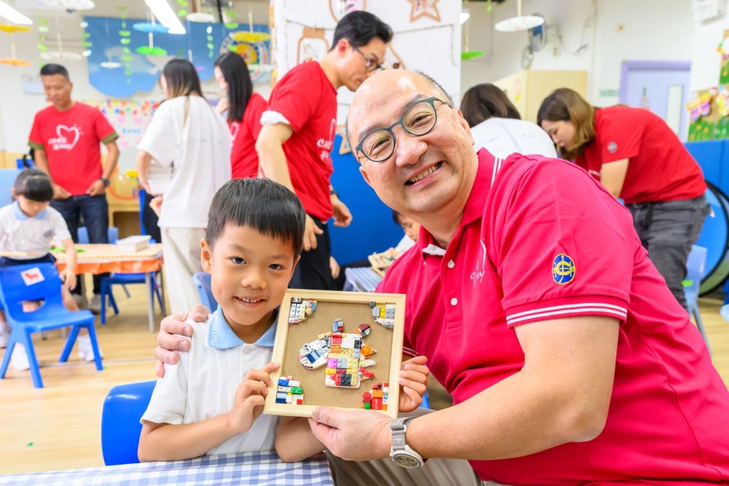 馬會公司事務執行總監譚志源（右）夥義工帶領幼稚園學童，一起將二手玩具創作成獨一無二的玩具畫，延長被遺棄玩具的生命，並教育小朋友珍惜玩具。