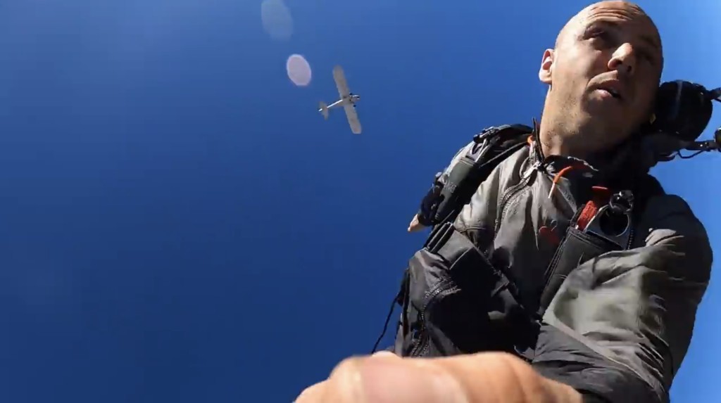雅各（Trevor Jacob）手持自拍棍跳伞，途中继续拍摄飞机去向。Youtube截图