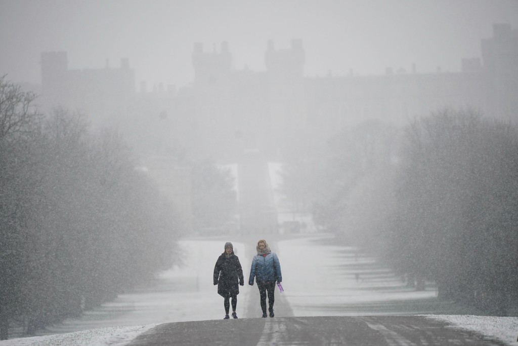 人们冒雪沿著通往伯克郡温莎城堡的 Long Walk 上行走。AP