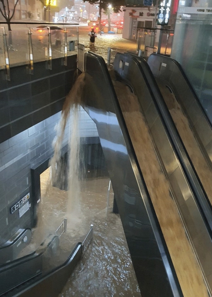 首爾一處地鐵站遭雨水灌入，滾滾泥水沿着樓梯奔騰而下，景象宛如大瀑布。