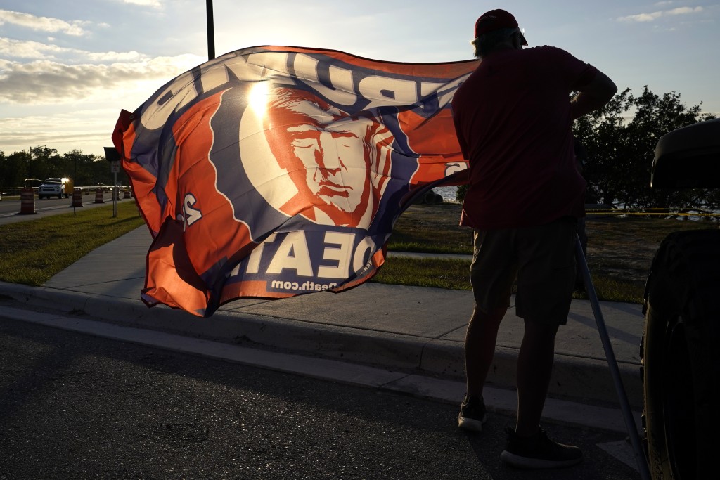 在佛羅里達州棕櫚灘，前總統特朗普的支持者在其海湖莊園外展開印有其肖像的旗幟。AP