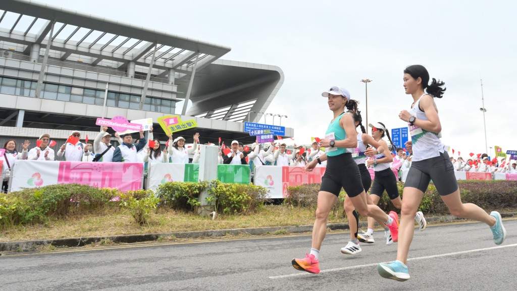 女子組參賽選手跑經深圳灣口岸，打氣隊伍在旁為運動員打氣。