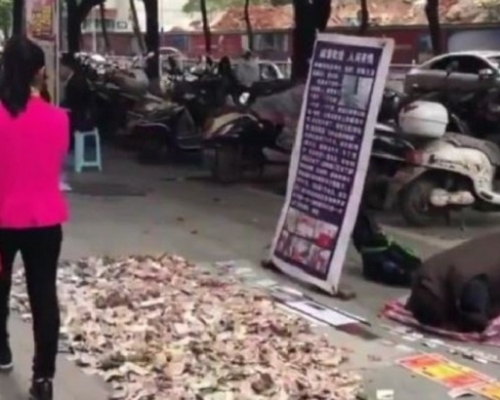 該男子在街頭行乞時,從袋中倒出一張又一張鈔票,並堆出一座「鈔票山」。