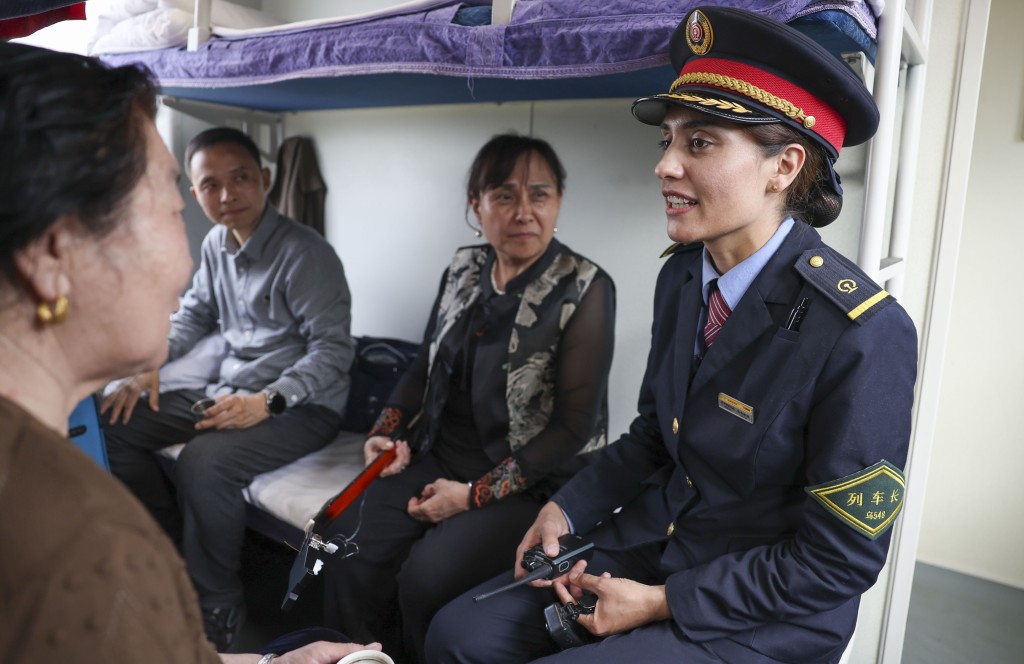 在由喀什開往成都西的列車上，艾爾開牙·多力開（右一）和旅客交談。 新華社