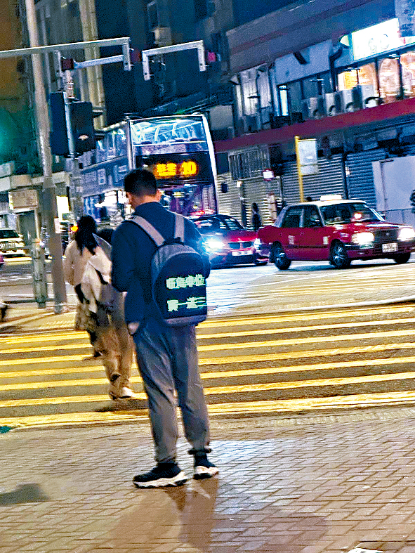 哥哥仔背囊上寫着「旺角車位，買一送三」。