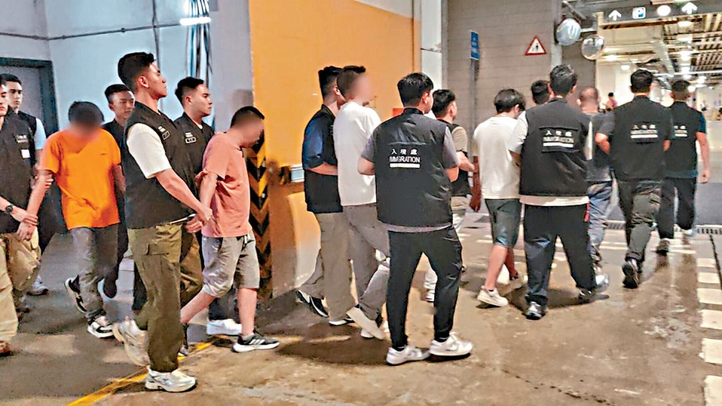 入境處將行動中拘捕人士押走。