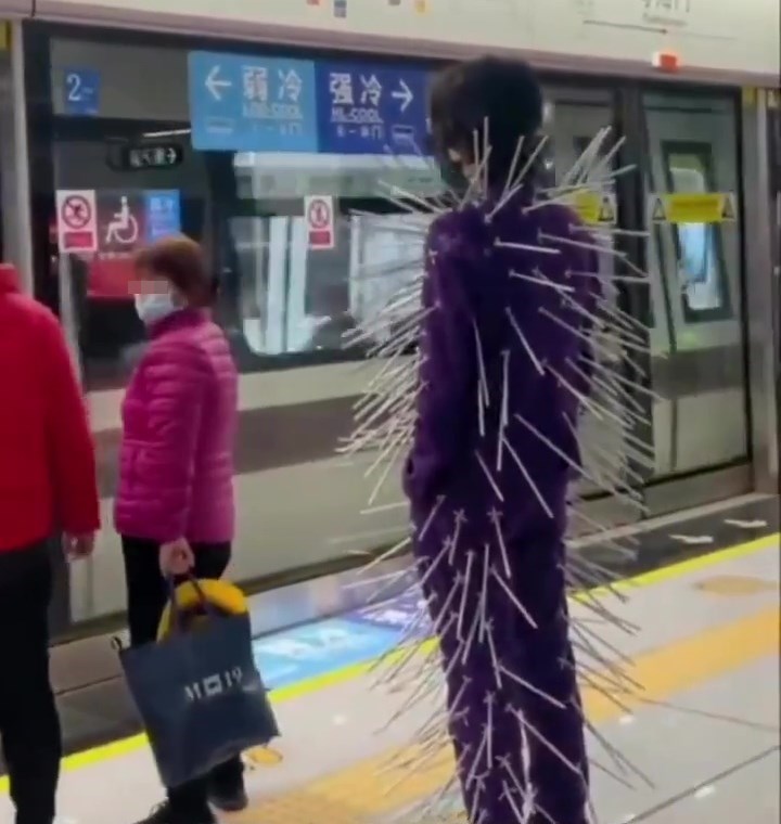 穿一身紫色「萬箭穿心西裝」的男子，自信地在人來人往的月台上候車。網上截圖