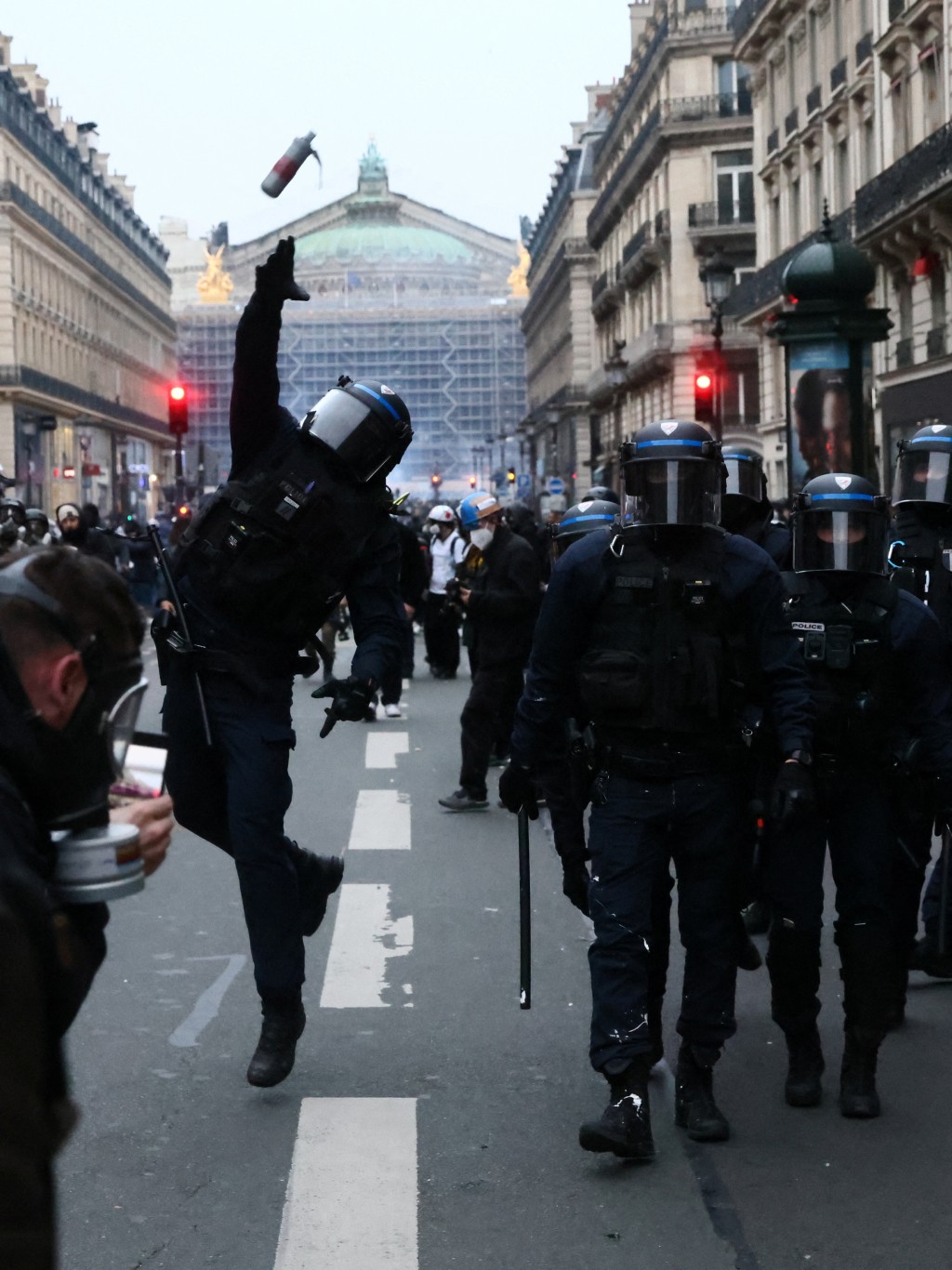 法國退休改革引發的全國示威進入第9天，巴黎歌劇院附近一名防日暴警員投擲催淚彈。 路透社