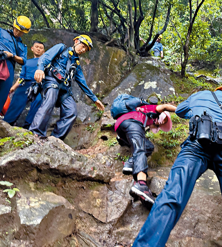 行山受傷婦人獲救後，由消防及救護員陪同步行落山送院。