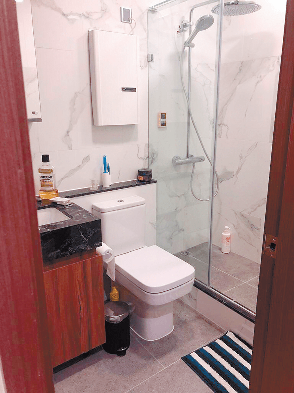 浴室用料講究，設有玻璃門分隔淋浴區。