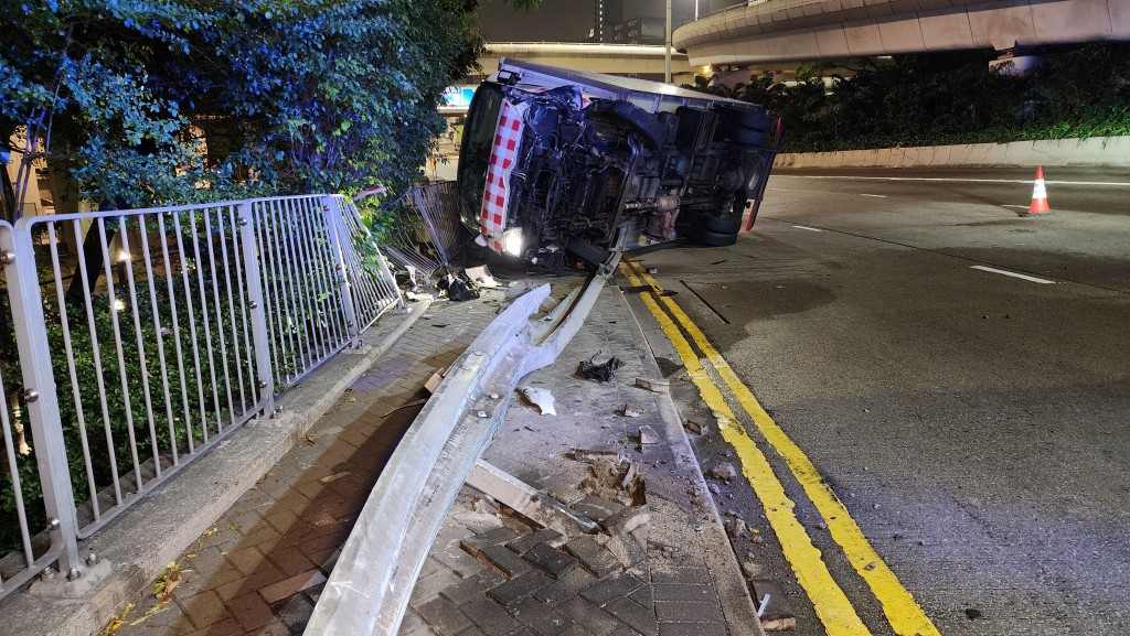 貨車翻側擱在防撞欄上。 貨車翻側擱在防撞欄上。