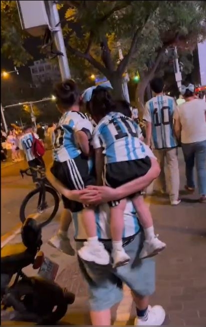 一男子背兩小童觀看阿根廷的比賽。