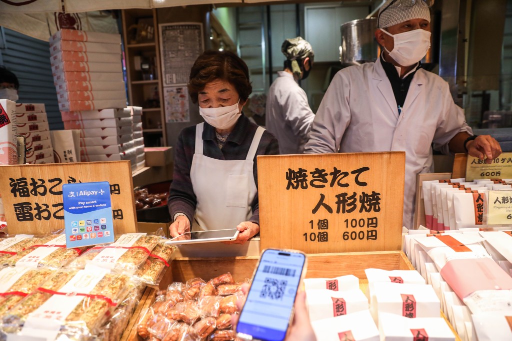 有游客用电子钱包购买当地传统小吃、号称浅草「三大名物」之一的人形烧。