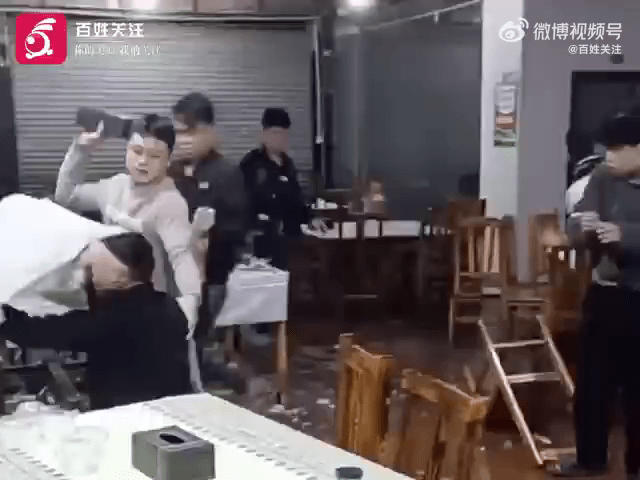 影片中，燒烤店發生群毆，一名男子被枱布蒙頭，有人拿起紙巾盒等雜物打他。