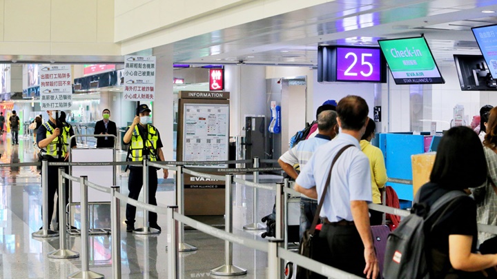 台灣近日出現誘騙民眾到柬埔寨的求職陷阱，警員要在機場舉牌提醒出境人士防範。中時圖片