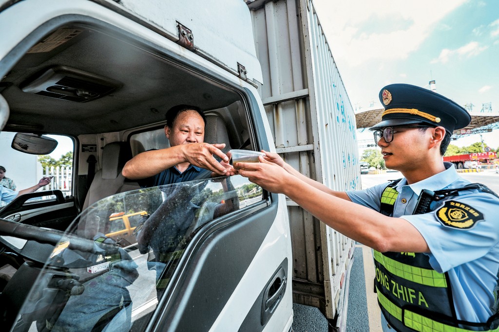 交管人員為長途貨車司機送上防暑降溫飲品。