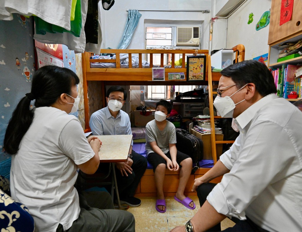 2022年7月30日，李家超（右二）在政務司司長陳國基（右一）陪同下，探訪居住於「劏房」的基層家庭，了解其生活狀況。