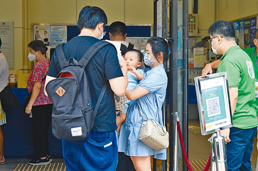 家長抱着數月大的小孩輪候打針。