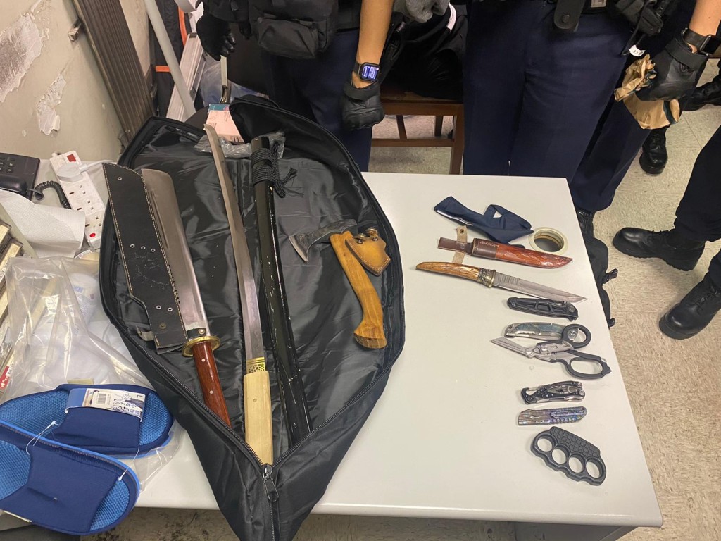 警员在两名被捕男子的袋中发现多把长刀及斧头。  ​