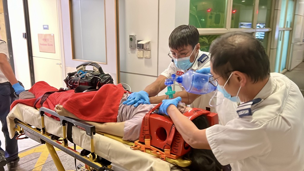女事主被送往醫院時,救護員為她施以心外壓急救。
