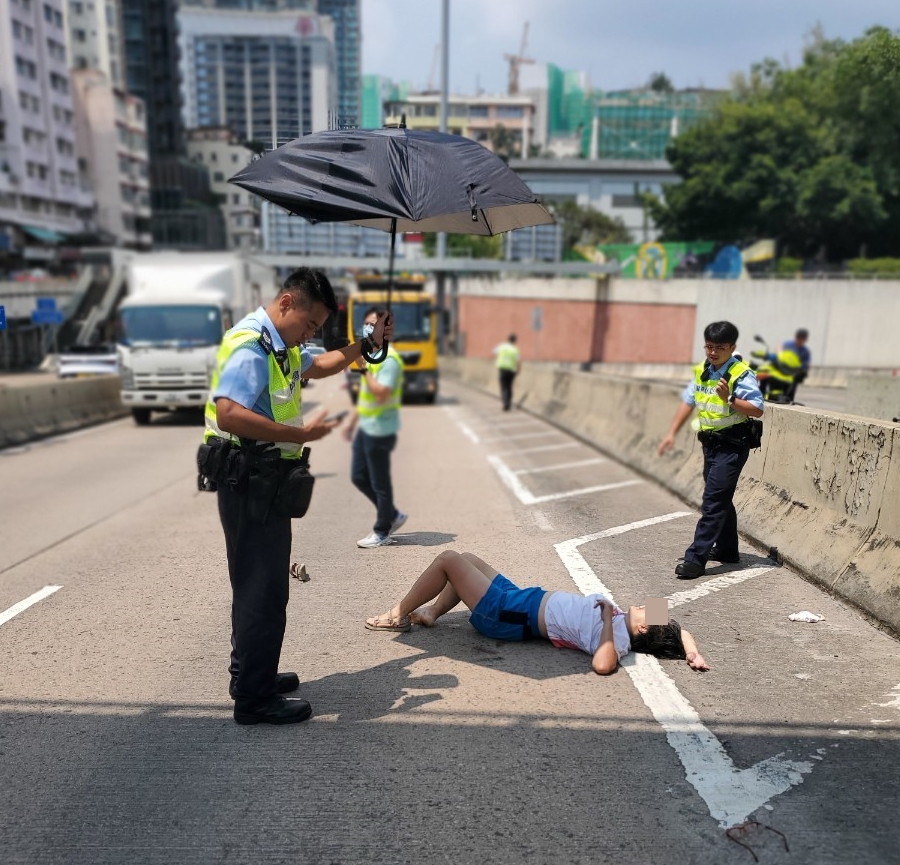 女子跳橋倒地受傷，警員為她打傘避免曝曬。