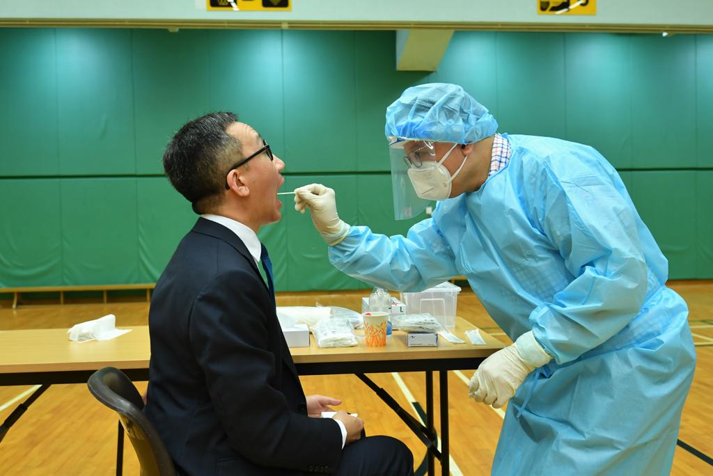 許樹昌及梁卓偉先後穿上保護衣、戴上手套及面罩等,為對方進行採樣
