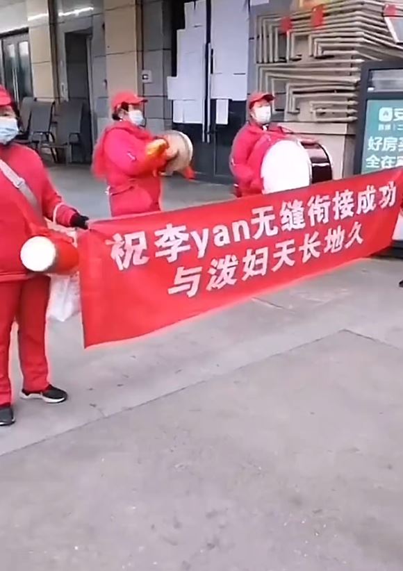 红衣大妈锣鼓队在街上拉起横额替女事主报复「渣男」。影片截图