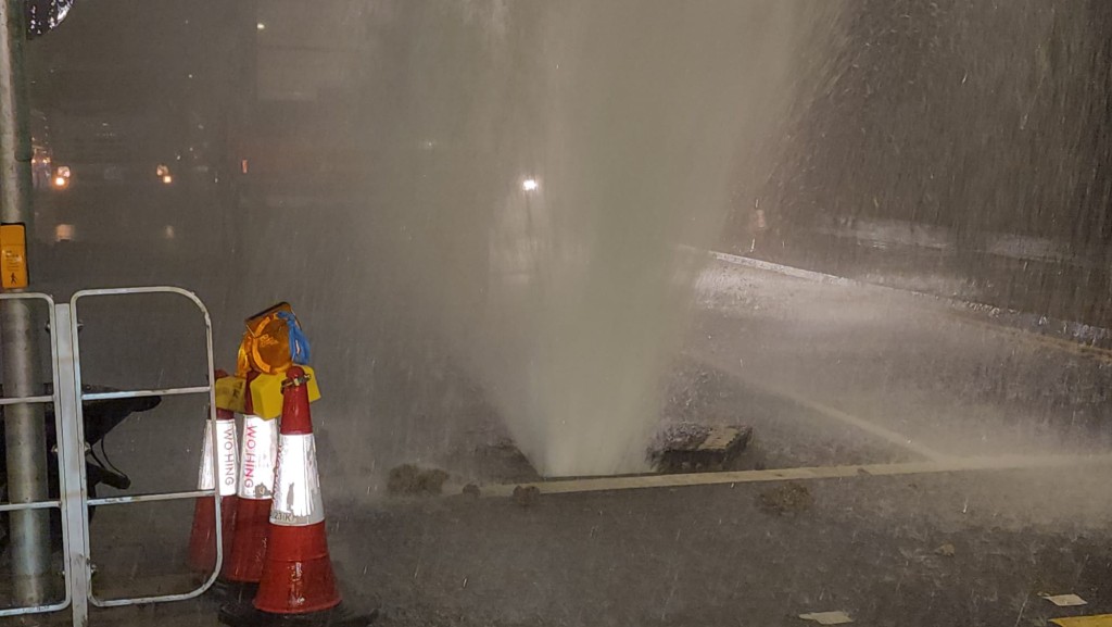 強大的水壓瞬間衝破路面渠蓋。黎志偉攝