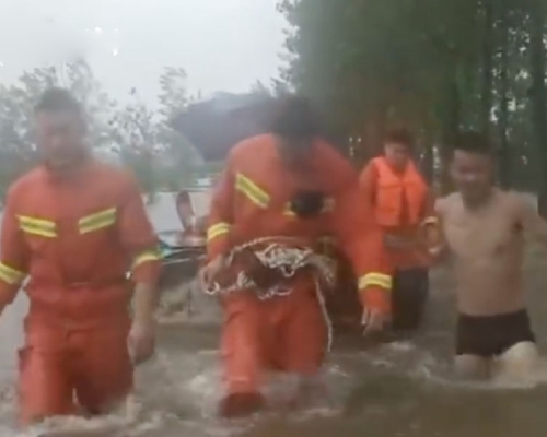 消防員在水中行走拖拽體能損耗巨大,手臂用不上勁就把衝鋒舟用繩綁在腰間,在洪水中拖拽衝鋒舟奮力前行。(網圖)